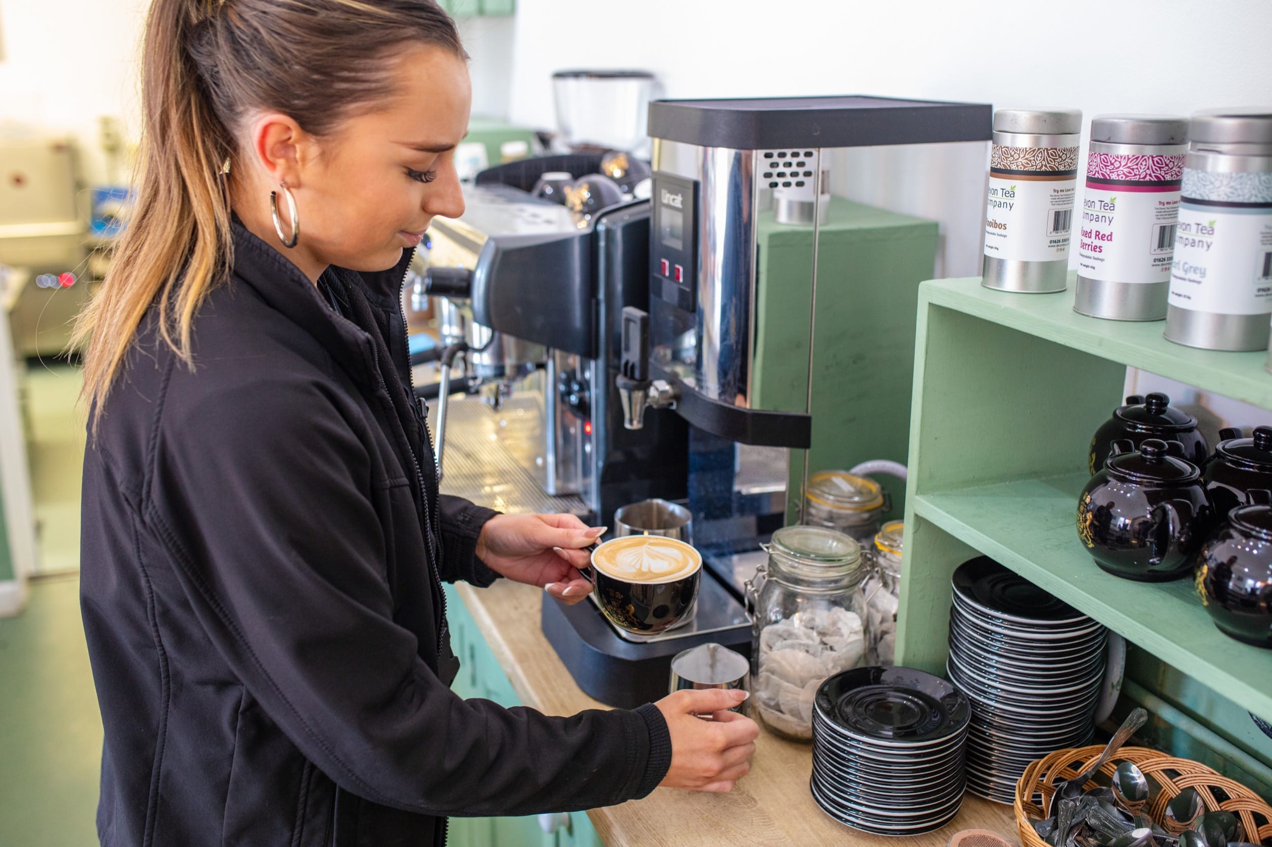 A woman prepares coffee for a customer